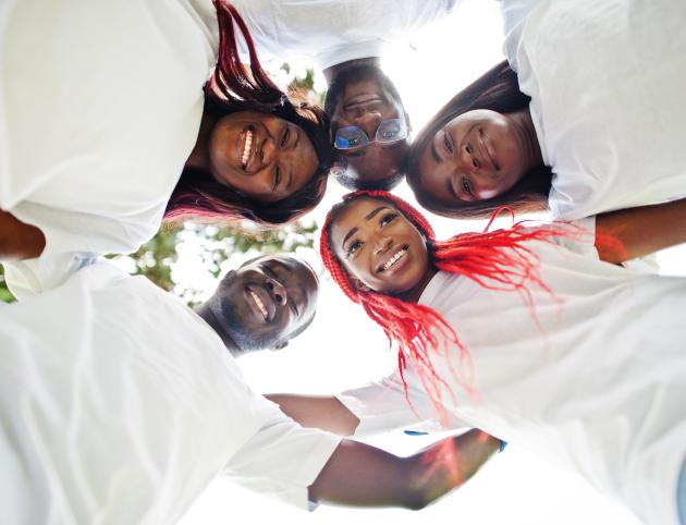 Group of happy african volunteers hugs in park. Africa volunteering, charity, people and ecology concept. Look from down.